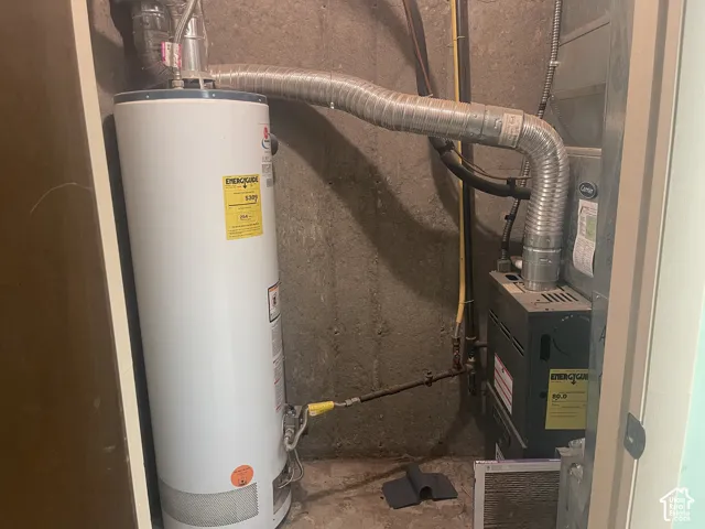 Utility closet containing a water heater, a gas-fired furnace, and flexible metal ductwork against a concrete foundation wall