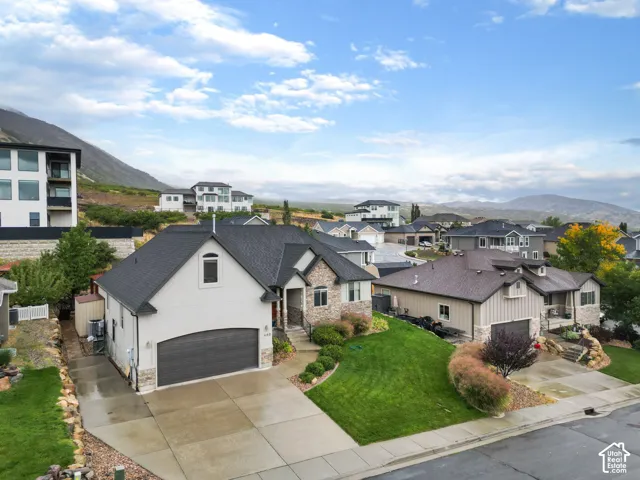 Stucco and stone exterior, asphalt shingle roof, attached two-car garage, concrete driveway, and mountain backdrop