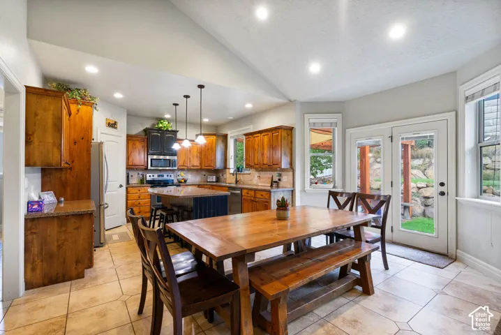 Kitchen featuring vaulted ceilings, wood cabinetry, a central island with countertop, recessed lighting, and tile flooring