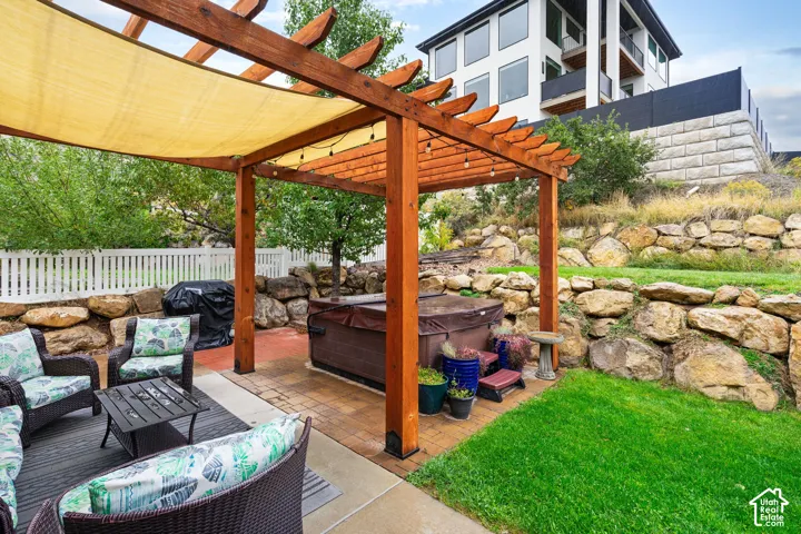 Outdoor living space featuring a cedar pergola, paved patio, multi-level stone retaining walls, and a manicured lawn