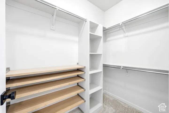 Walk-in closet featuring white built-in shelving, wooden shoe racks, and metal hanging rods