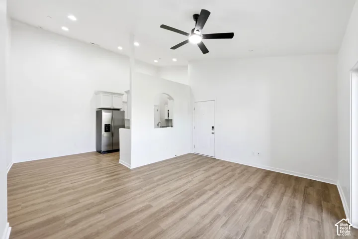 Vaulted ceilings, wood-finish flooring, recessed lighting, ceiling fan, and architectural archway detail