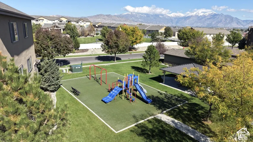 Common area featuring a playground with slides and swings, a covered pavilion, manicured green space, and mountain scenery