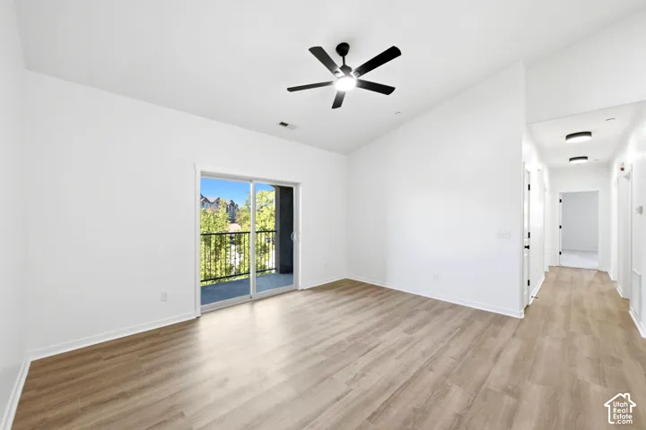 Vaulted ceilings, wood-finish flooring, ceiling fan with integrated lighting, sliding glass door, and balcony access