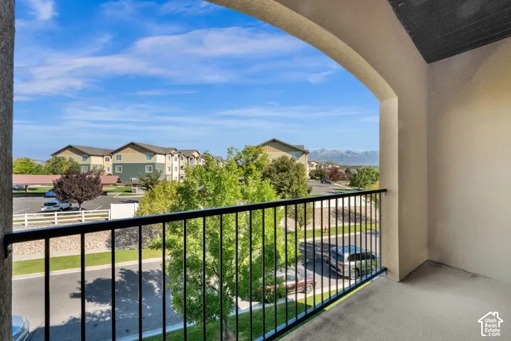 Covered balcony featuring an arched entryway, smooth concrete flooring, and a black metal railing