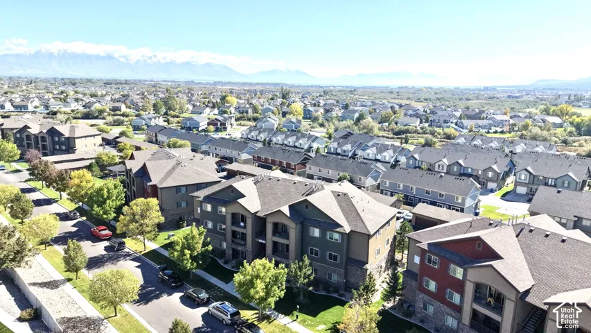 Aerial perspective of a multi-story residential complex featuring stone and siding exteriors, pitched roofs, private balconies, and a mountain backdrop