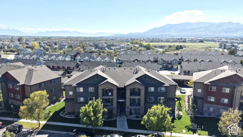 Aerial perspective featuring multi-story residential buildings with stone and siding exteriors, pitched roofs, and surrounding landscaped grounds against a mountain backdrop