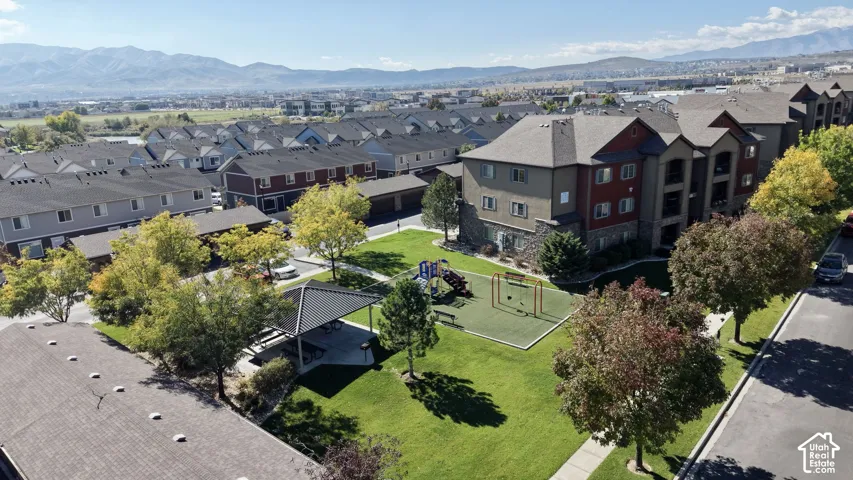 Common recreation area featuring a pavilion, playground structure, manicured lawn, and mature trees with a mountain backdrop