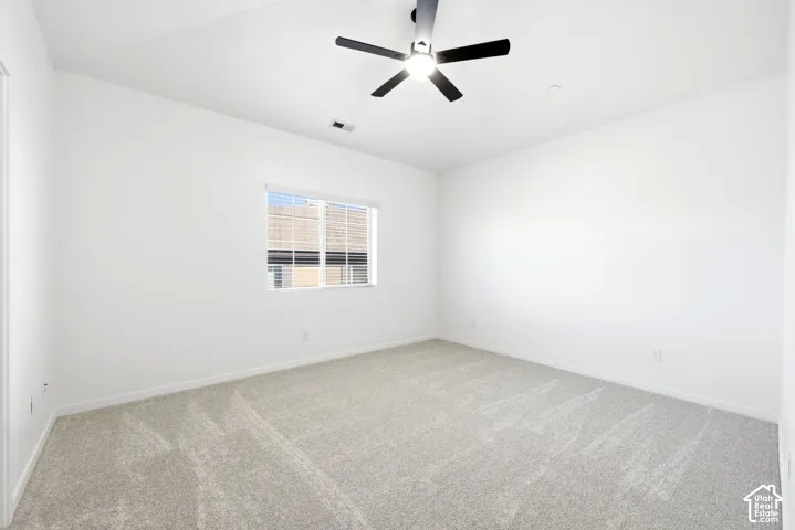 Vaulted ceiling, neutral wall-to-wall carpeting, and a multi-blade ceiling fan with integrated lighting