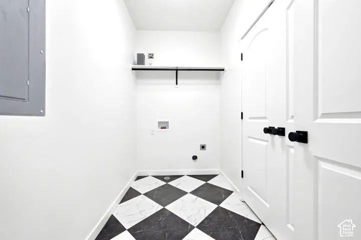 Utility space featuring a checkered tile floor, built-in wall shelf, double-panel interior doors with matte black hardware, and dedicated hookups for laundry appliances