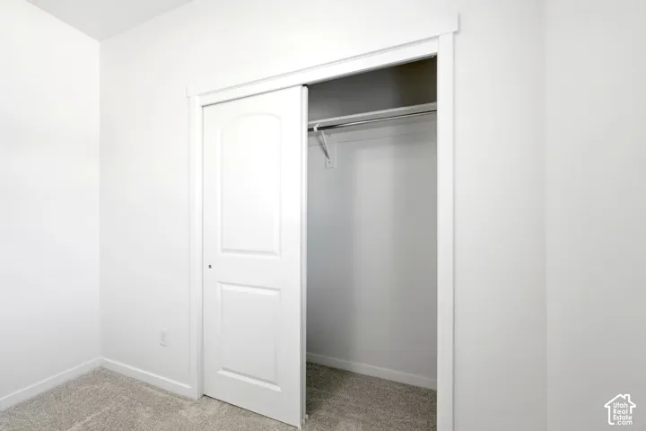 Reach-in closet featuring a sliding two-panel door, neutral carpeting, and a built-in metal garment rod