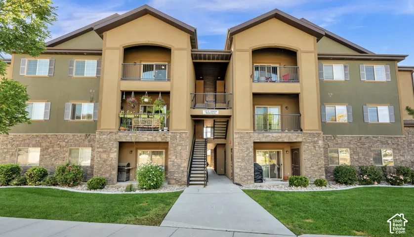 Multi-story exterior featuring a stone masonry facade, stucco siding, dual balconies with metal railings, and a central exterior staircase