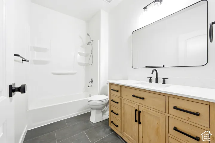 Bathroom featuring wood-finish cabinetry, white countertop, rectangular mirror with black frame, matte black hardware, and gray tile flooring