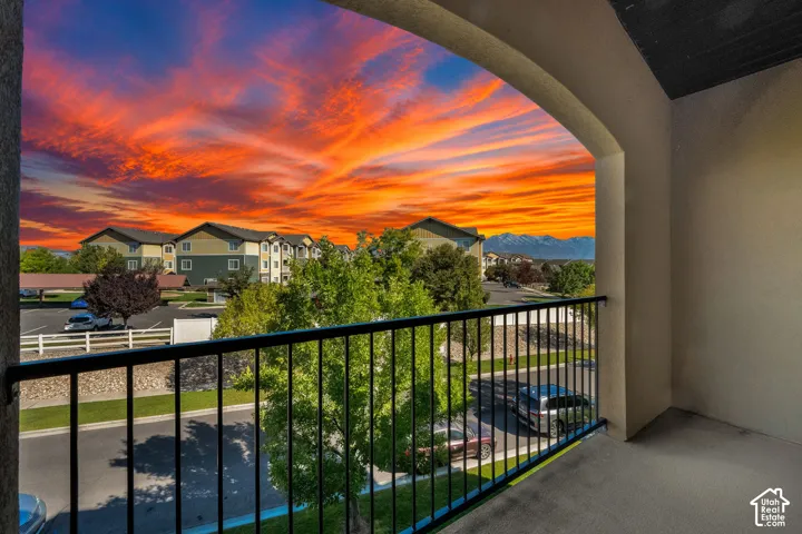 Covered balcony featuring arched architectural detailing and black metal railings with mountain and sunset scenery