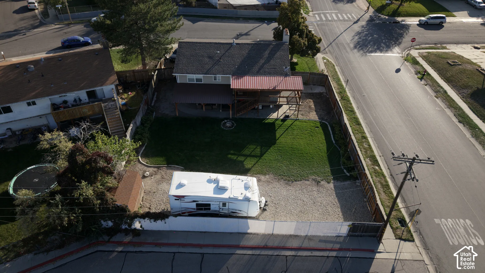 Backyard featuring a covered deck, stone-bordered lawn, gravel parking area, and perimeter wood fencing