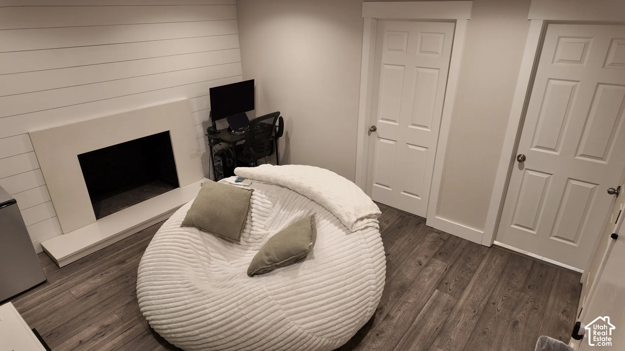 Interior space featuring a fireplace with a minimalist surround, horizontal shiplap wall treatment, wood-finish flooring, and two six-panel doors