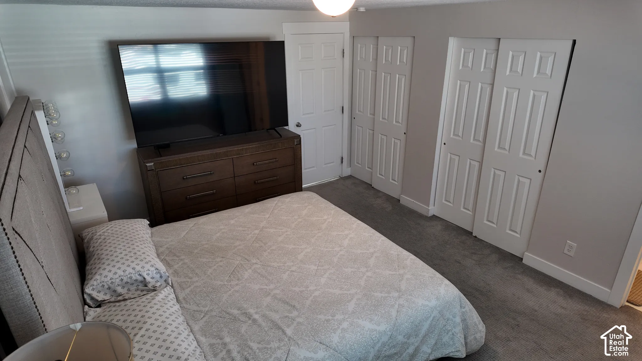 Room featuring neutral-toned carpeting, two sets of white six-panel closet doors, and a single six-panel interior door with brushed nickel hardware