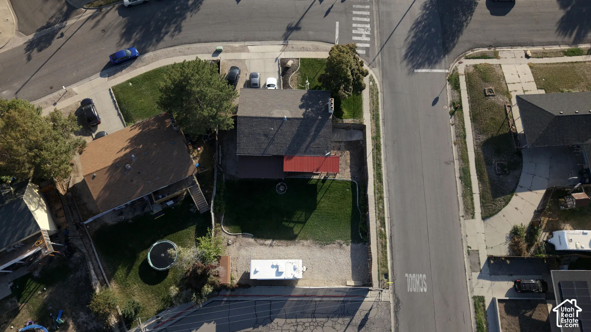 Corner lot property featuring an asphalt-shingle roof, a rear concrete patio with a metal awning, a fenced backyard, and a gravel storage area