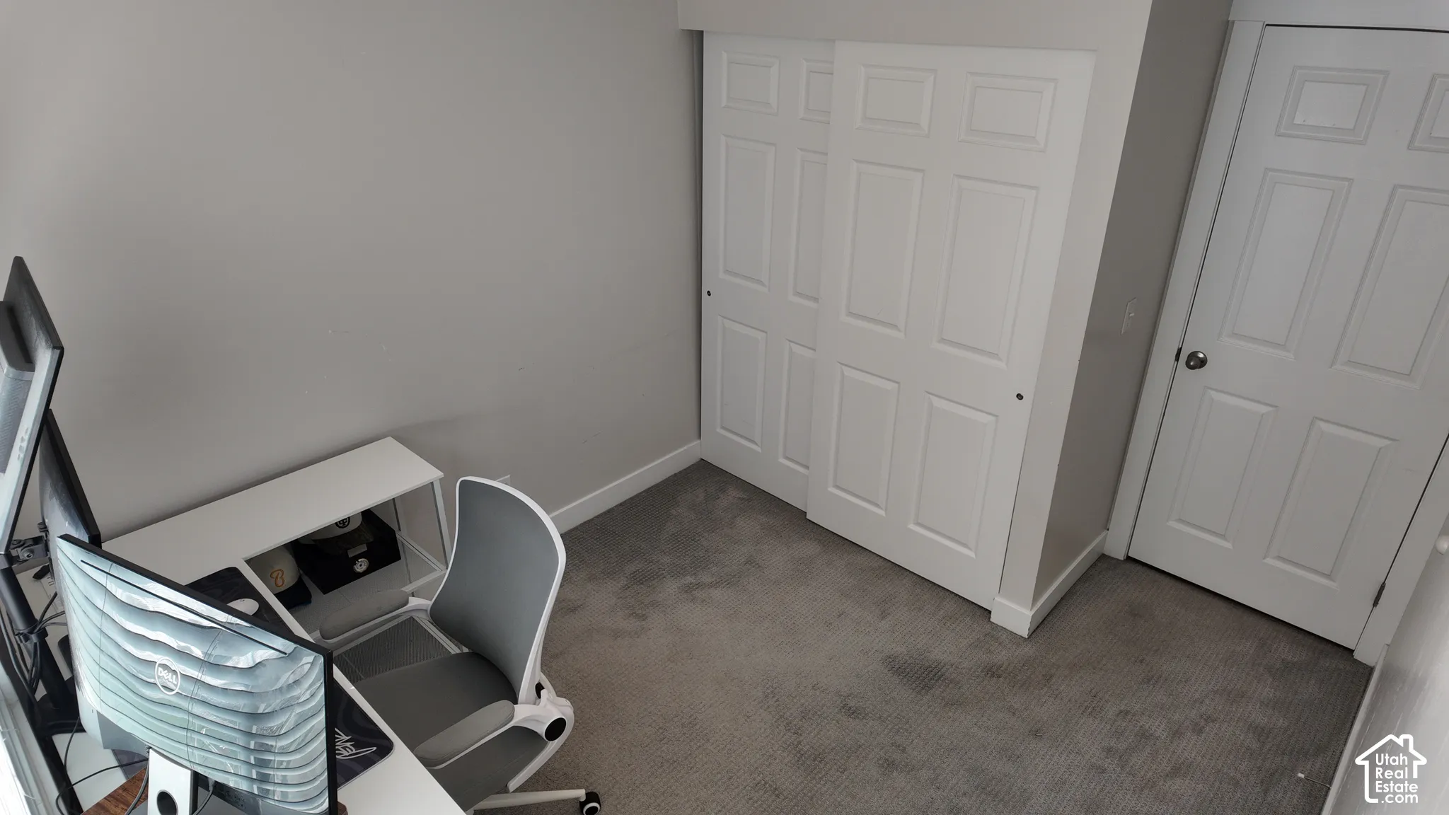Neutral-toned room featuring plush wall-to-wall carpeting, sliding panel closet doors, and a standard interior swing door