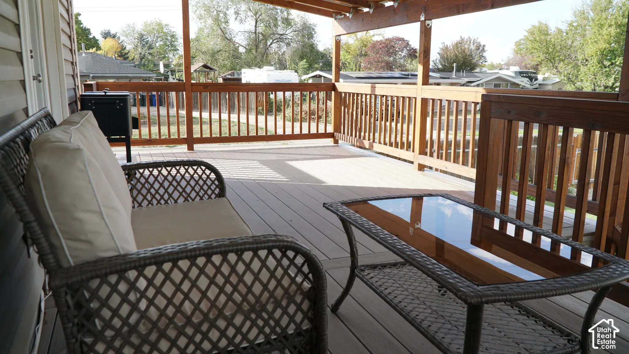 Covered deck featuring composite decking, wooden railing, and a pergola-style overhead structure