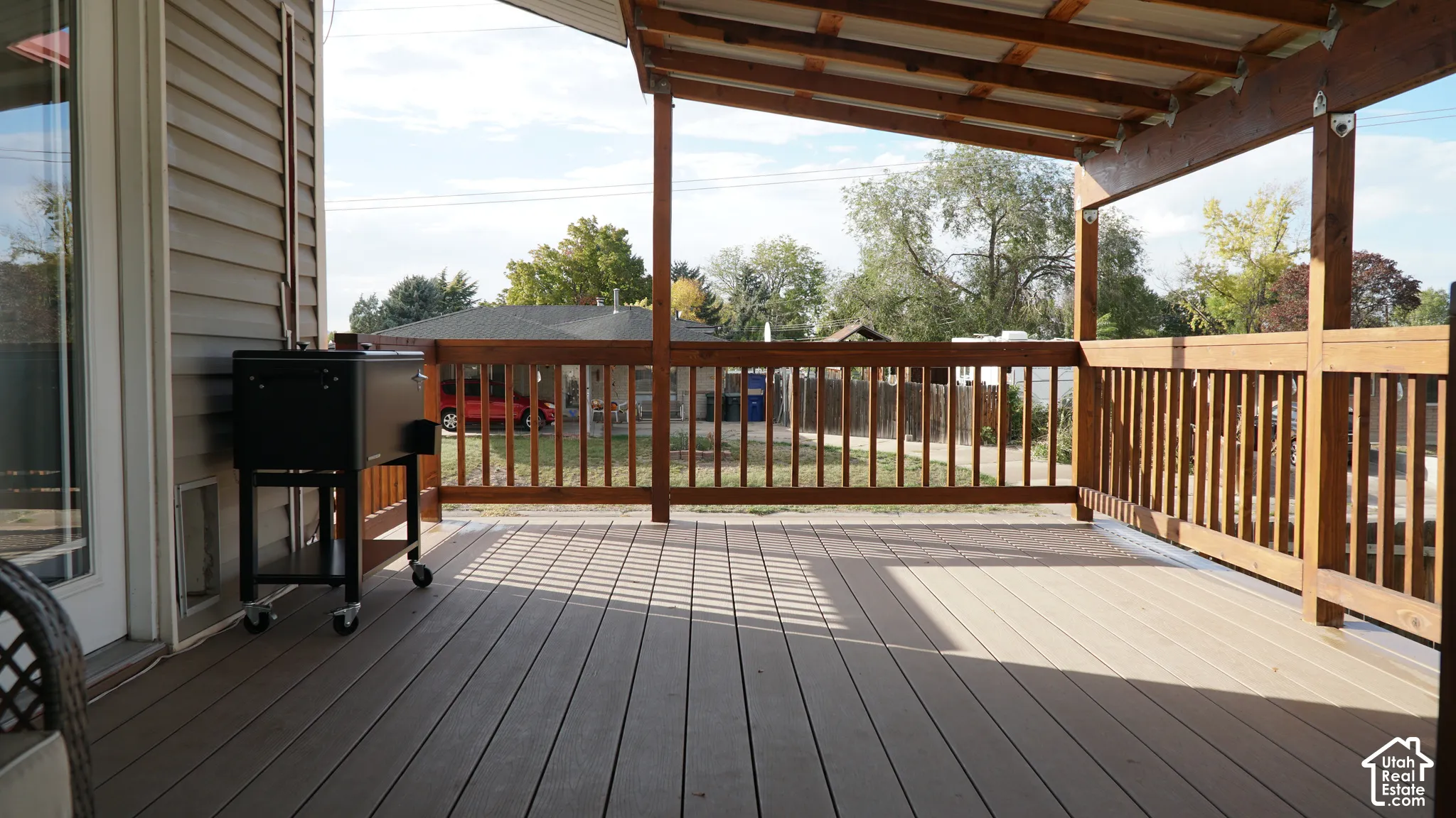 Covered deck featuring composite decking, wood railing, and vinyl siding exterior