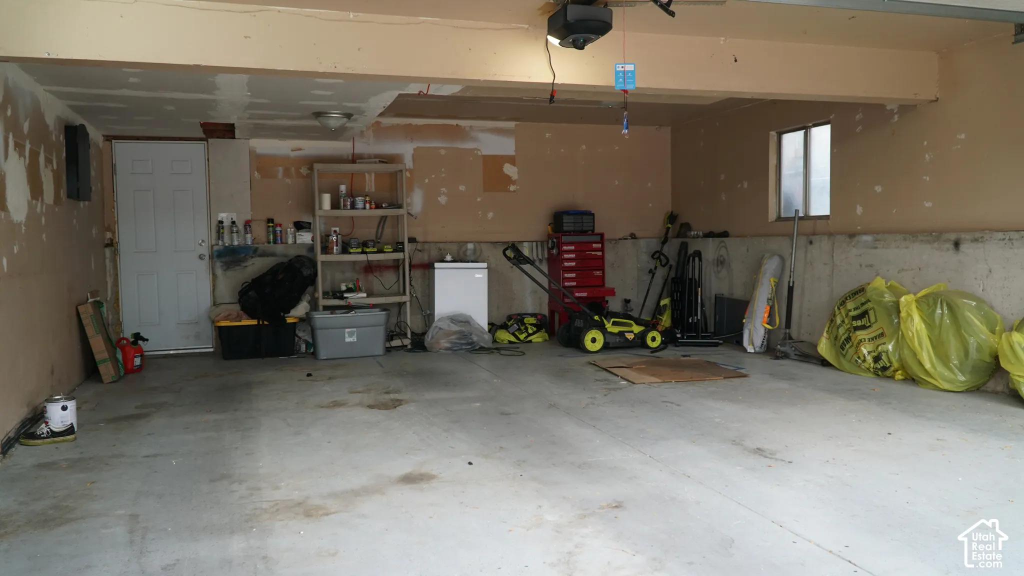 Two-car garage featuring a concrete floor, concrete foundation walls, single-pane window, and a white paneled swing door