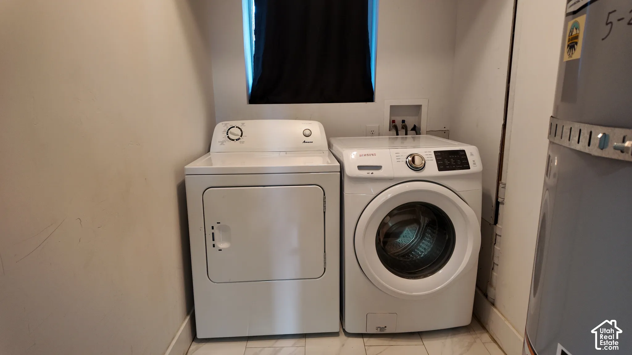 Laundry area featuring dedicated water and power hookups, a central window, and neutral tile flooring