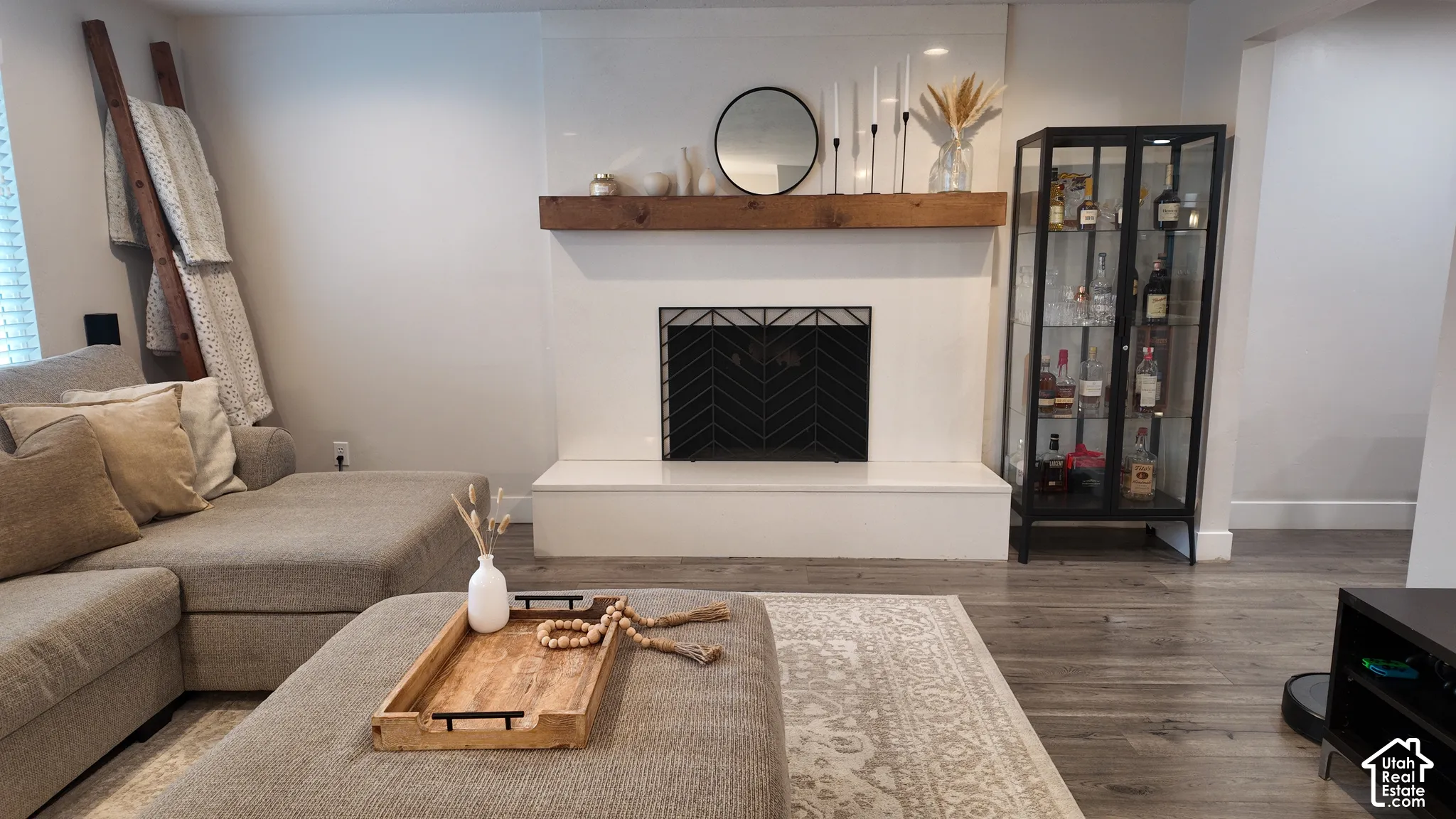 Fireplace featuring a smooth white hearth and surround, accented by a natural-finish wood mantel and a decorative geometric metal screen