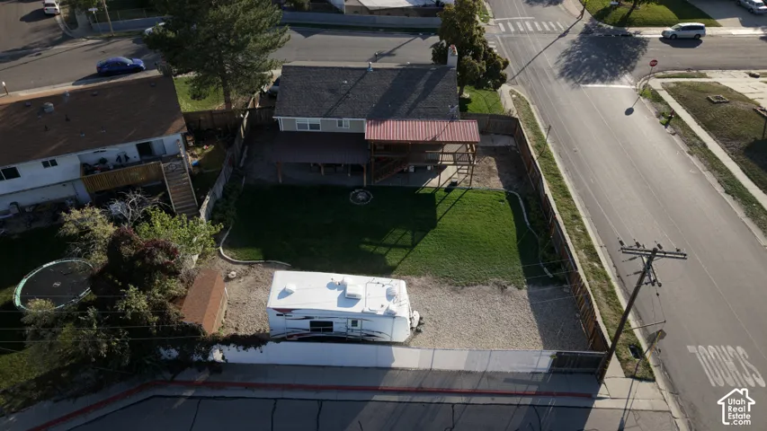 Backyard featuring a covered deck, stone-bordered lawn, gravel parking area, and perimeter wood fencing