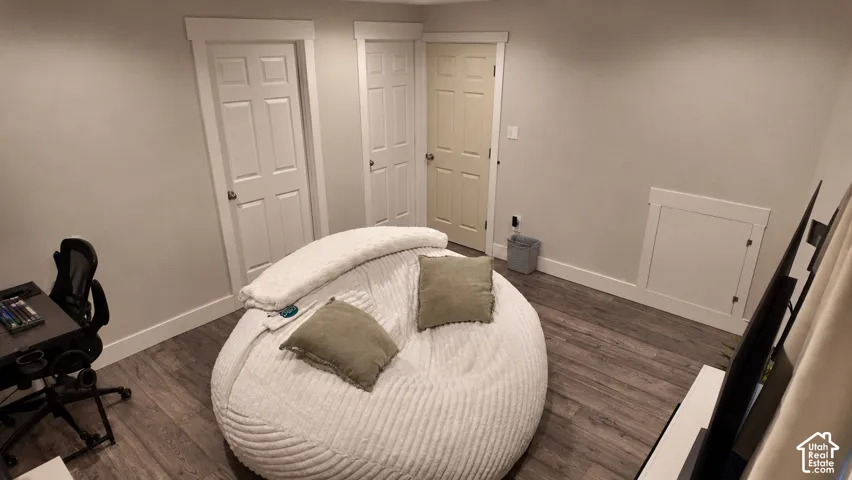 Room featuring wood-finish flooring, three interior doors with white trim, and a built-in wall access panel