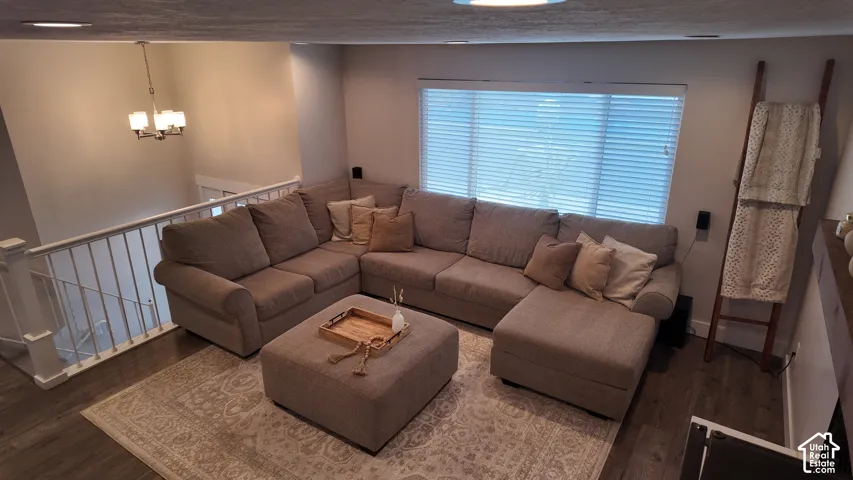 Living area featuring wood-finish flooring, recessed lighting, a multi-bulb chandelier, and a white balustrade railing