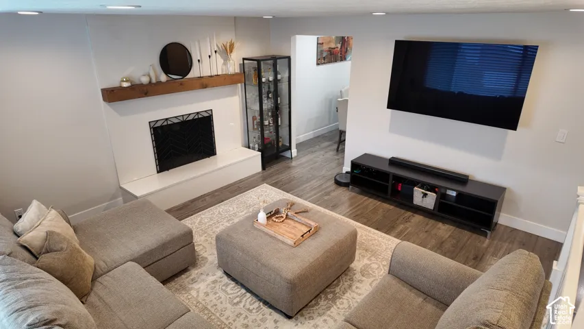 Fireplace with a wooden mantel, wood-finish flooring, and recessed ceiling lighting