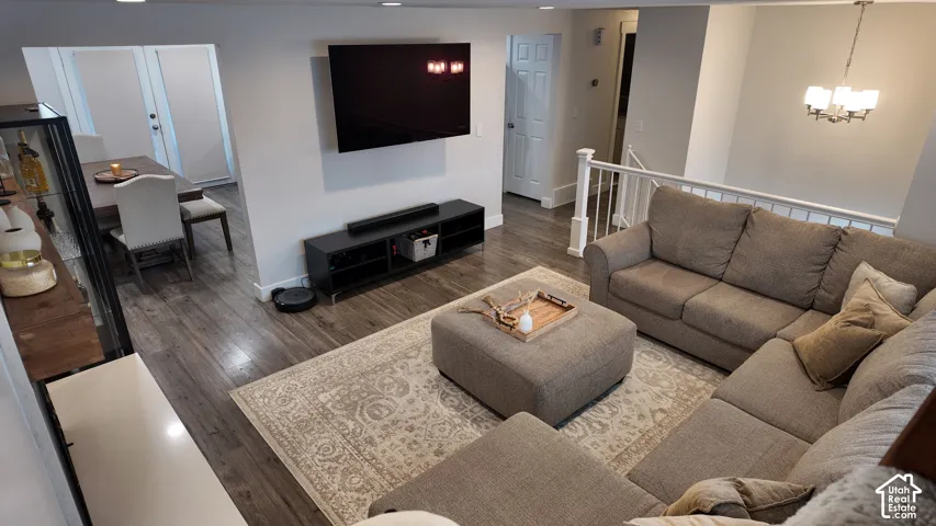 Open-concept interior featuring wood-finish flooring, recessed lighting, a white spindle stair railing, and a multi-light chandelier