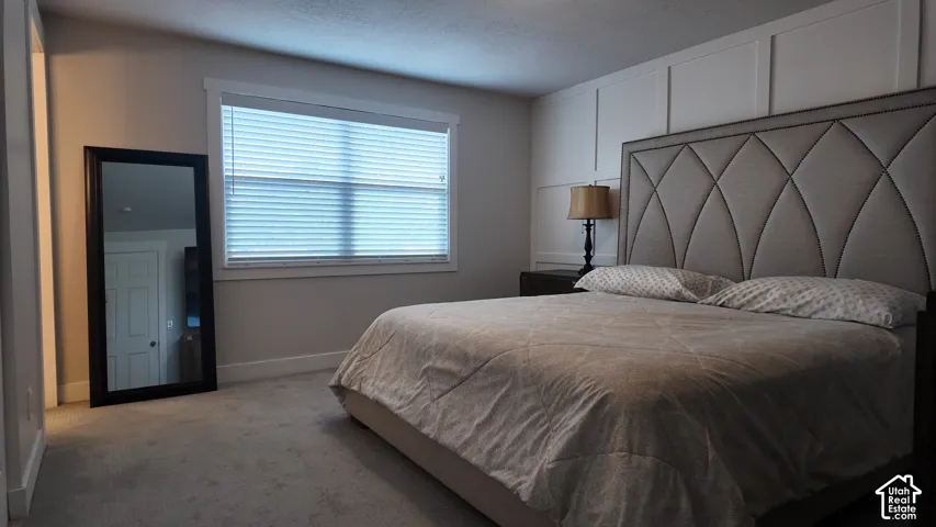 Wall-mounted grid molding accent wall, neutral carpeting, and horizontal slat window blinds