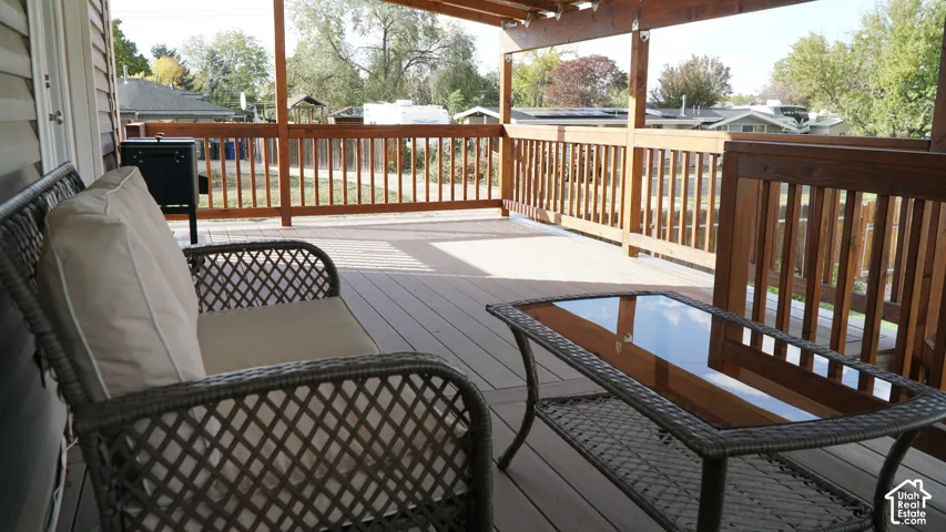 Covered deck featuring composite decking, wooden railing, and a pergola-style overhead structure