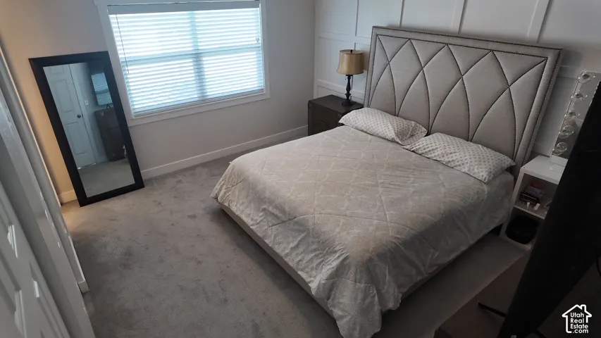 Neutral-toned carpeted flooring, wall paneling detail, and window with horizontal blinds