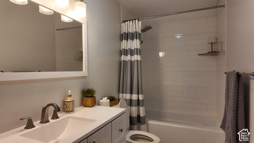 Bathroom featuring a white vanity with a rectangular basin, metallic finish faucet, framed mirror, and a shower-tub combination with white subway tile surround