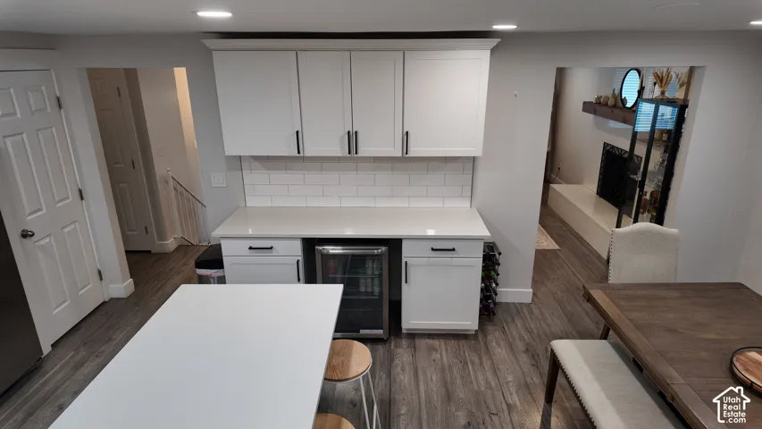 Custom wet bar featuring white cabinetry, quartz countertops, subway tile backsplash, built-in beverage refrigerator, and recessed lighting