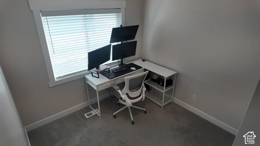 Neutral interior room featuring neutral-toned carpeting and a single window with horizontal blinds encased in white-painted trim