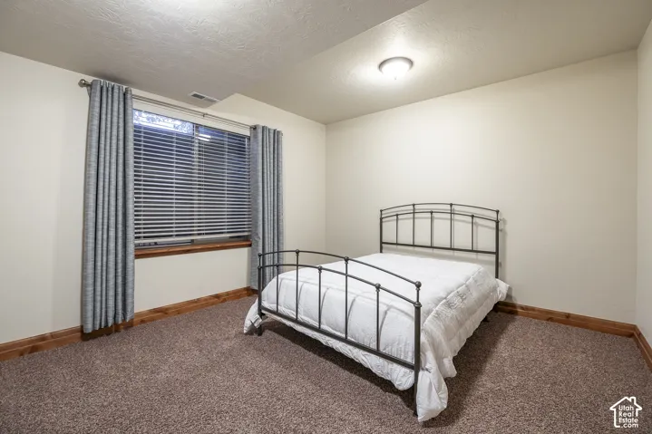 Neutral wall finishes, textured carpeting, large window with integrated blinds, and wood-finish trim detailing