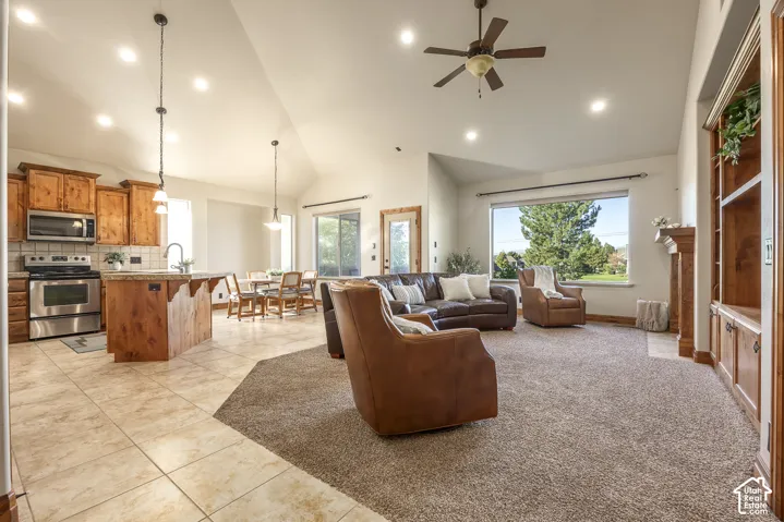 Vaulted ceilings featuring recessed lighting and a ceiling fan, kitchen with wood cabinetry and a central island, and built-in floor-to-ceiling shelving