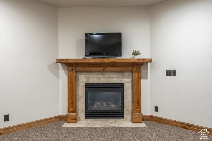 Corner fireplace featuring a stained wood mantel, tile surround, and black metal hearth