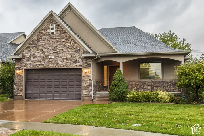 Exterior featuring a stone facade, stucco siding, a gabled roofline, a covered porch, and an attached two-car garage