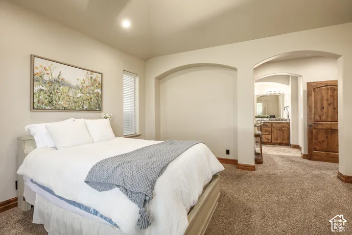Vaulted ceiling with recessed lighting, arched architectural alcove, and wood-finish interior door