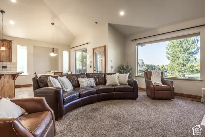 Vaulted ceilings featuring recessed lighting, large picture window, pendant lighting, and wood-finish cabinetry