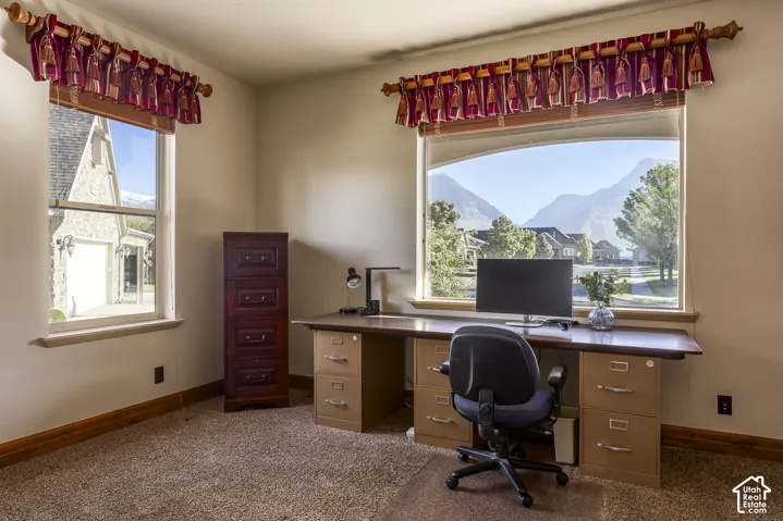 Room featuring carpeted flooring, large picture windows, and a mountain backdrop