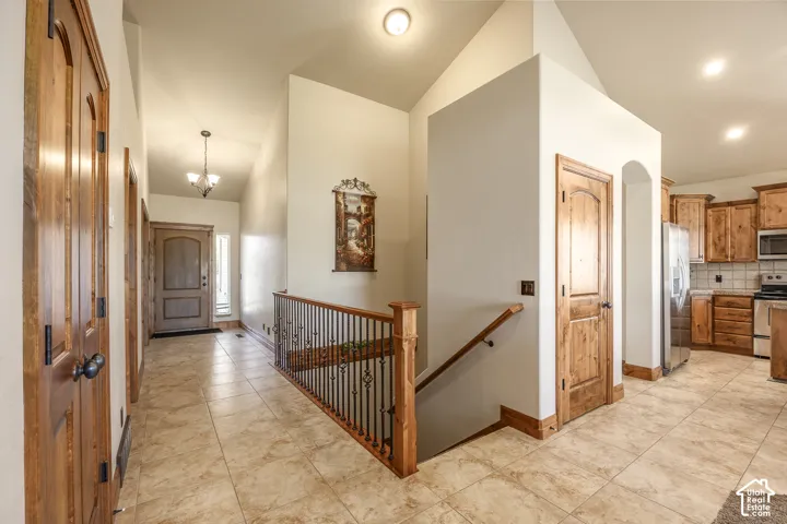 Vaulted ceilings with recessed lighting, tile flooring, stained wood interior doors, and custom staircase railing featuring metal spindles and wood handrail