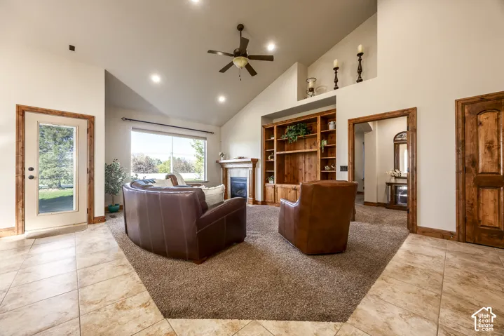 Vaulted ceilings, built-in wooden shelving, stone-surround fireplace, tile flooring, and wood-trim door frames