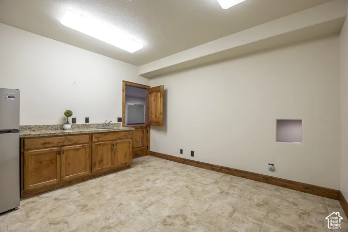 Built-in cabinetry with stone-finish countertops, stainless steel sink basin, tile flooring, and solid wood trim