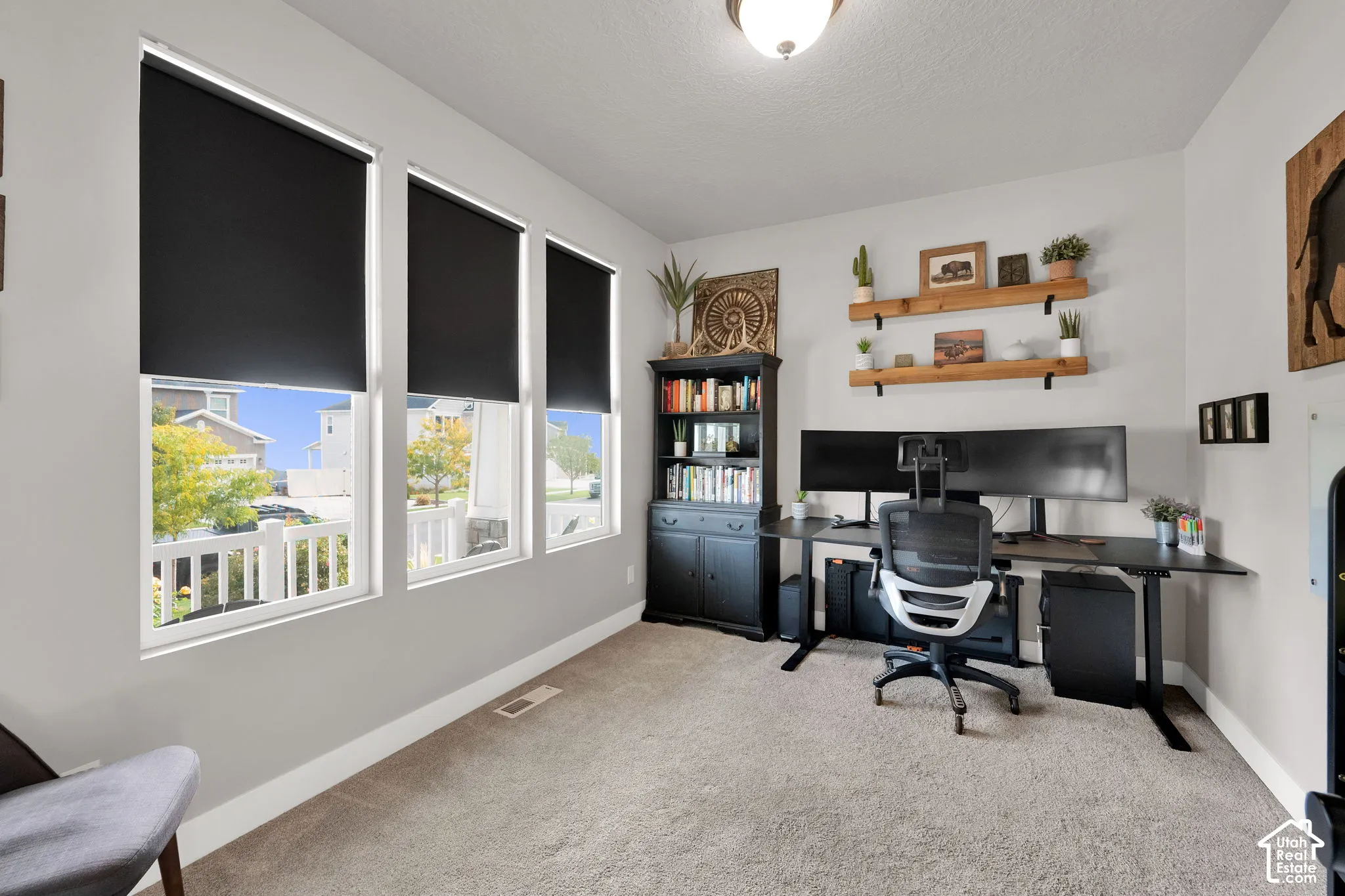 Neutral wall tones, carpeting, triple-window configuration, and wall-mounted shelving